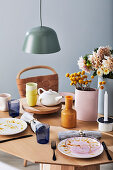 Gedeckter Tisch mit Teekanne, Vasen und Blumen