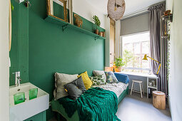 Scatter cushions on bed and sink in room with green accent wall