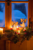 Arrangement of sheet-music angels and candles in rustic window