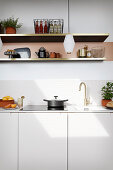 A white kitchen counter with an open shelf above it and pendant lamp hanging from the ceiling