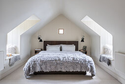 Double bed in bedroom with opposing windows and window seats