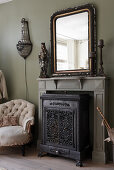 An antique mirror on the mantelpiece above a cast iron stove
