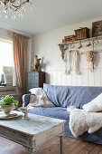 A sofa with a blue cover and a sheepskin in a shabby-chic style living room