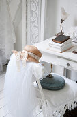 A white chair with tulle and a lady's hat on a desk