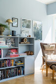 A bookshelf and a comfortable chair in front of the window in a living room