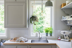 A sink in front of the window in a bright kitchen