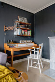 A desk and an open shelf in a guest room with a dark wall