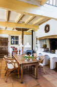 Wooden table with rattan chairs in front of wood stove in country house kitchen