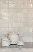 White saucepans on hob against glazed white splashback tiles