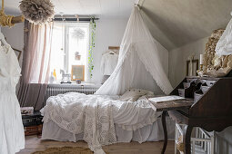 Bed with canopy next to antique bureau in girls' bedroom