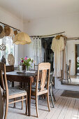 Rustic dining area, mirror, doorway with door curtain and dresses hung from pole