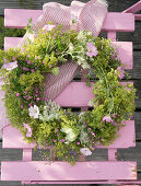 Wreath of lady's mantle, mallows, Queen Anne's lace and gypsophila hung on chair backrest