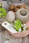 Egg covered in twine, green viburnum and saxifrage flowers