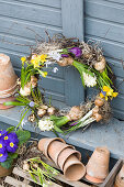Wreath with grape hyacinths, hyacinths, narcissus, crocus and star-of-Bethlehem and pot of blue primulas