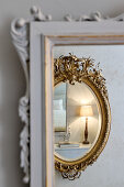 Reflection of a bedside lamp in gilt-framed mirror