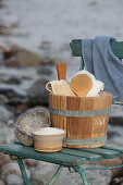 Antique sauna bucket and bathroom utensils on old wooden chair on beach