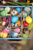 Colourful Easter eggs in wooden crate