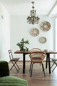 Esstisch mit verschiedenen Stühlen und Wandteller in hellem Zimmer