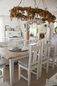 Wreath of dried flowers and chandelier above dining table
