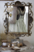 Woman in a vintage dress reflected in an ornate standing mirror
