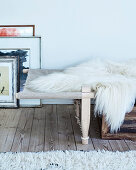 Couch with fur blanket next to pictures on wooden floorboards
