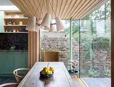 Dining area in extension with glass walls and wood cladding