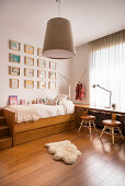 Gallery of pictures on wall above bed in child's bedroom decorated in shades of brown