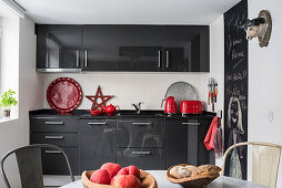 Red accents in grey and white kitchen with blackboard wall panel