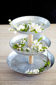 Flowers on homemade cake stand made from pewter plates and wooden rod