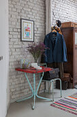 Vintage metal table and chair and coat rack against white-painted brick wall