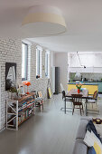 Offener Wohnraum mit weiß gestrichener Ziegelwand und grau lackierten Dielen