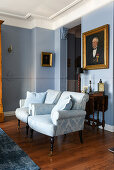 Two pale blue armchairs in classic living room with blue walls