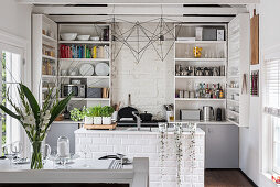 Open-plan kitchen in white with brick island counter