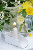 Lit candle next to posy of primroses, buttercups and tulips
