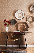 Desk against the wall below round baskets on geometric wallpaper