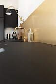 Black kitchen with gold backsplash and faucet fixtures