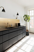 Modern black kitchen with golden splashback