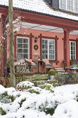 A view from a snowy garden of a veranda with a seating area