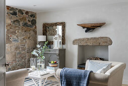 Kleine Sofas und Tisch in gemütlichem Wohnzimmer mit unverputzter Steinwand