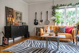 Schwarzes Sideboard, gelbes Sofa und Gitarren im Wohnzimmer
