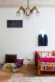 Colourful blanket on sofa with wooden frame, coat hanger above with neon light