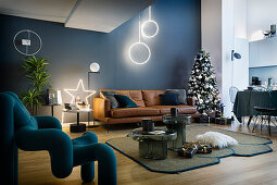 Ledersofa, Weihnachtsbaum und Designerstuhl im Wohnzimmer mit blauer Wand