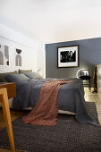 Queen bed with gray bedding and throw in bedroom