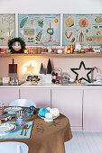 Blick über gedecktem Weihnachtstisch auf Einbauküche mit rosa Fronten und Regal