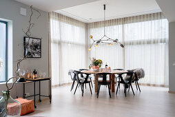 Dining area in front of floor-to-ceiling windows with curtain in open-plan kitchen dining area