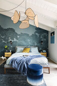 Queen bed in front of forest wallpaper and Viennese cane hanging lamp in bedroom with sloping ceiling