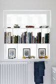 Bücherregal mit Miniatur-Fahrzeugen vor Fenster