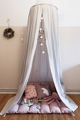 Fabric canopy over blanket, cushions and toys in child's bedroom
