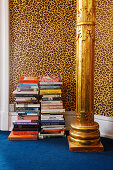 Stacked books, golden pillar and leopard-print wallpaper