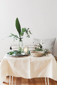 Sommerlich gedeckter Tisch mit mediterranem Blattgrün